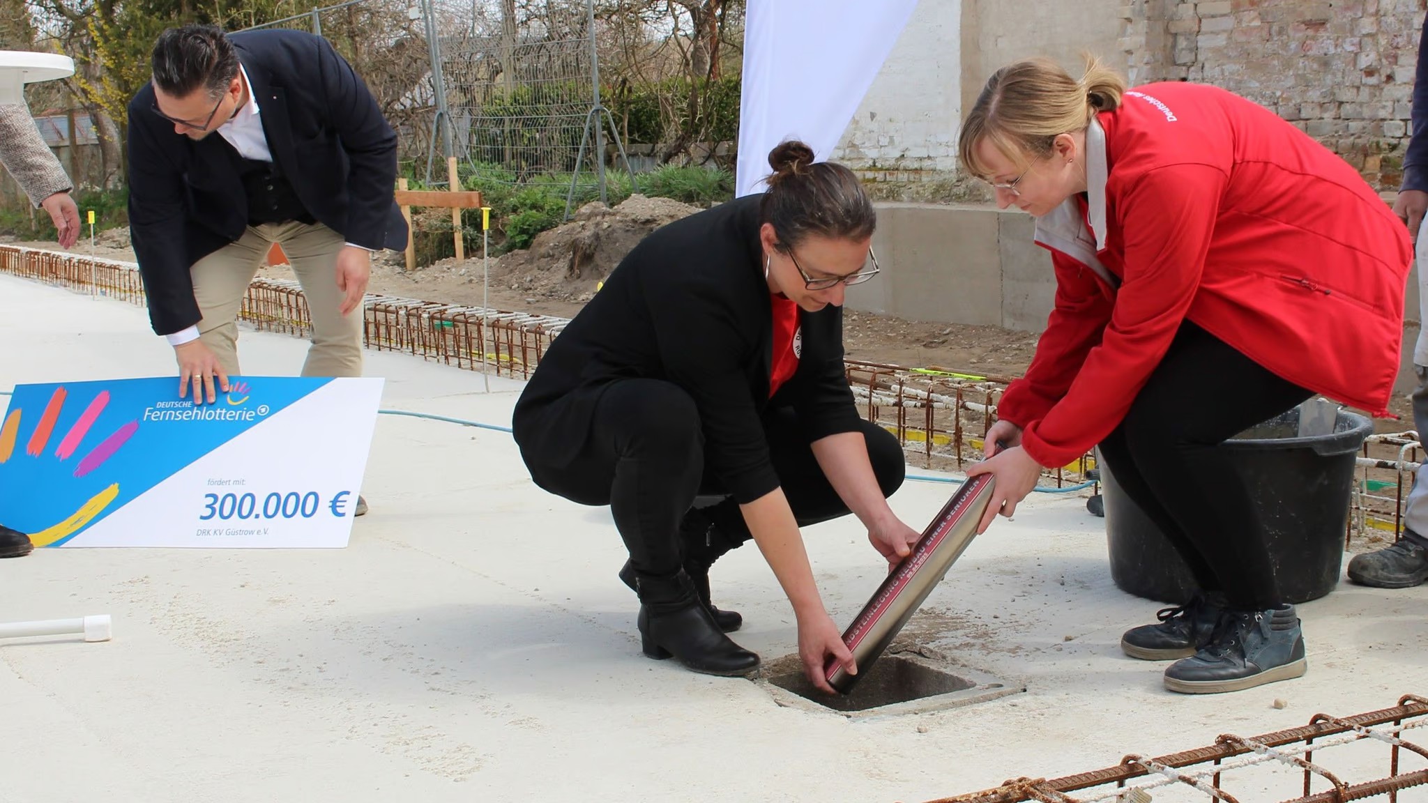 Bild zeigt Jenny Mendonca und Maria Henneberg beim legen der Zeitkapsel in das Fundament des Hauses für die Seniorengemeinschaft.