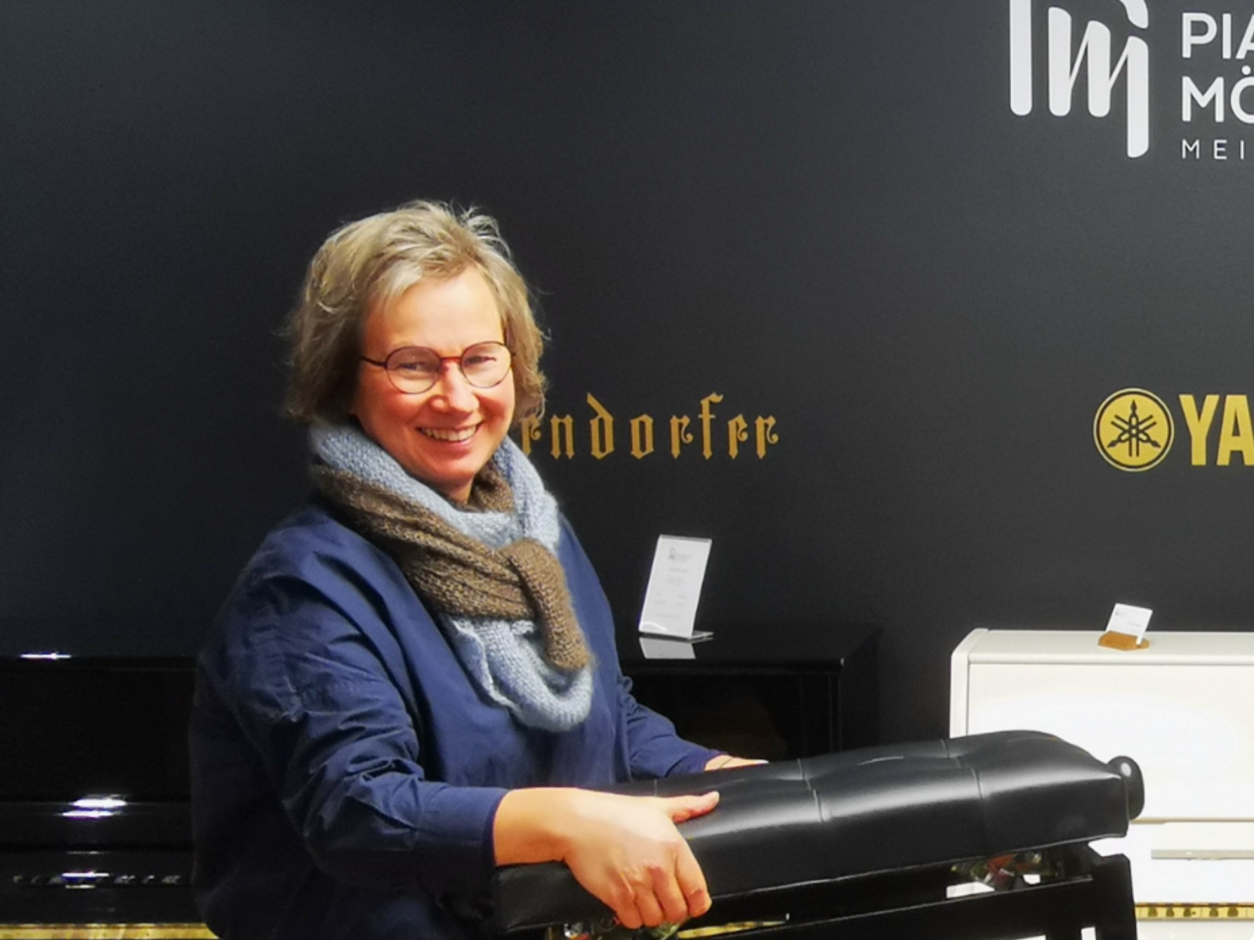 Bild zeigt Frau Petra Möller vom Pianohaus Möller mit dem Klavierhocker in der Hand
