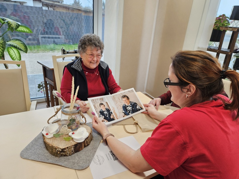 Bild zeigt Pflegefachkraft Anja Walter beim betrachten der Bilder zusammen mit Tagesgast Karin Wolfensteller