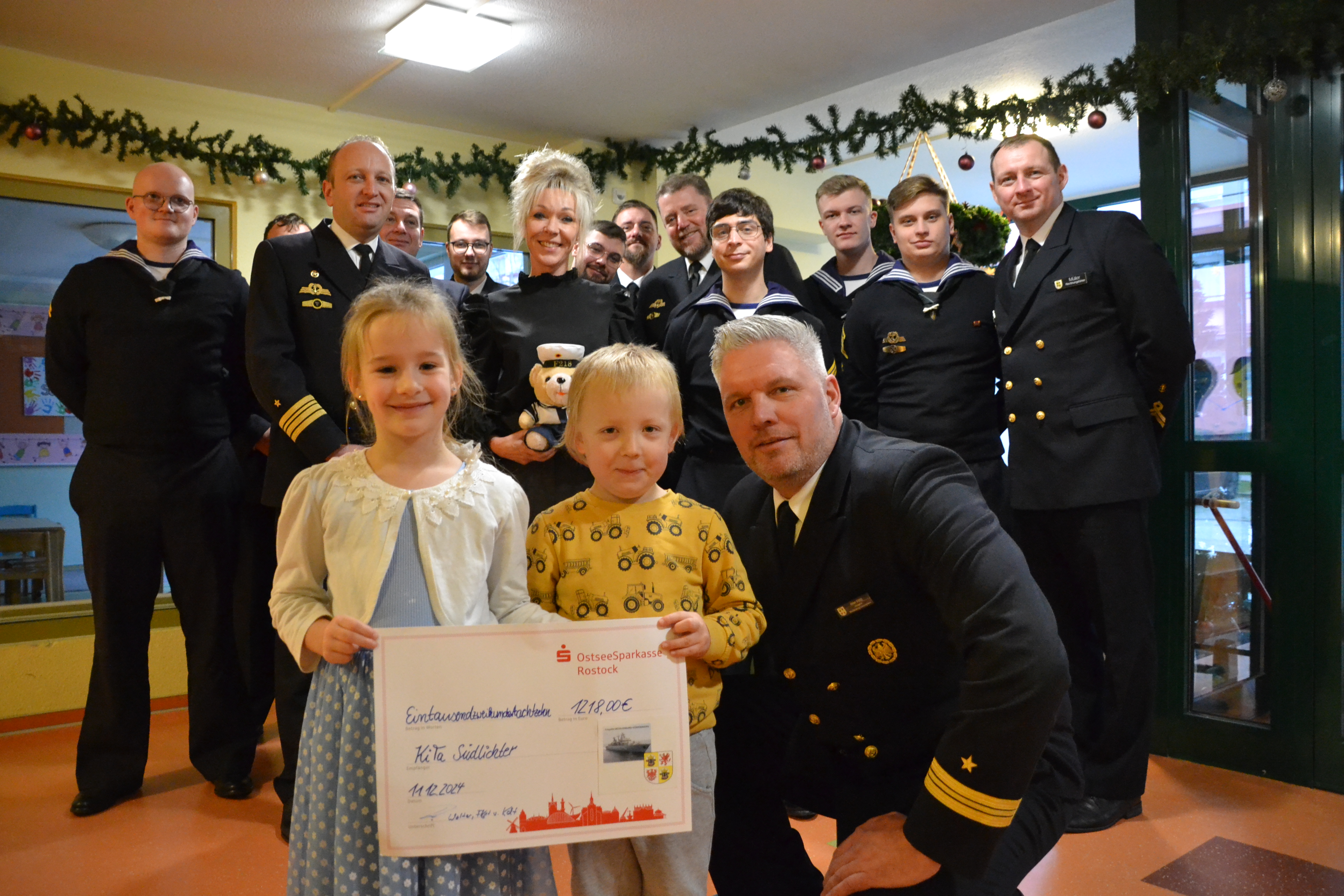 Bild zeigt Kinder und Marinesoldaten bei der Scheck-Übergabe