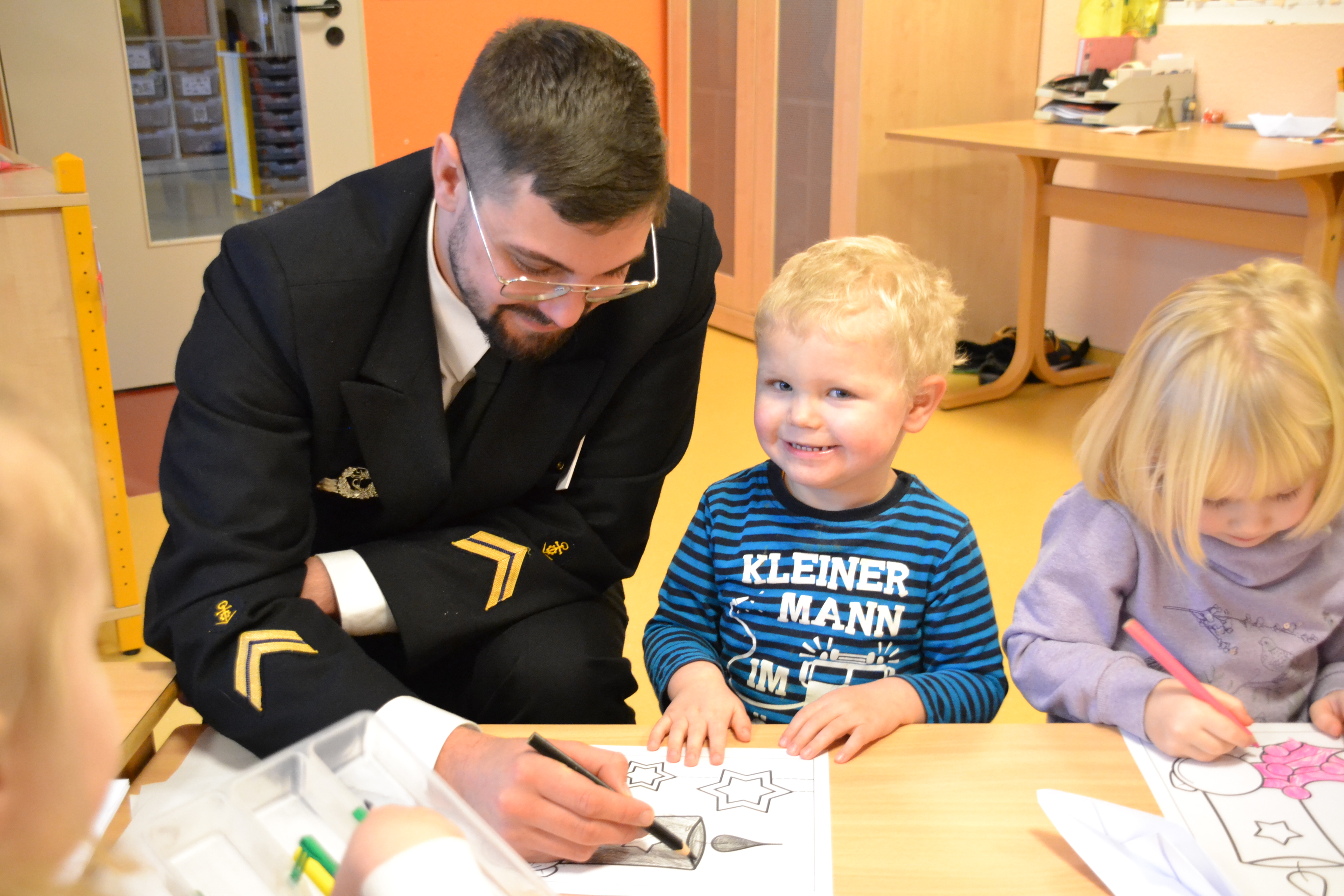 Bild zeigt einen Marinesoldaten mit Kindern beim zeichnen