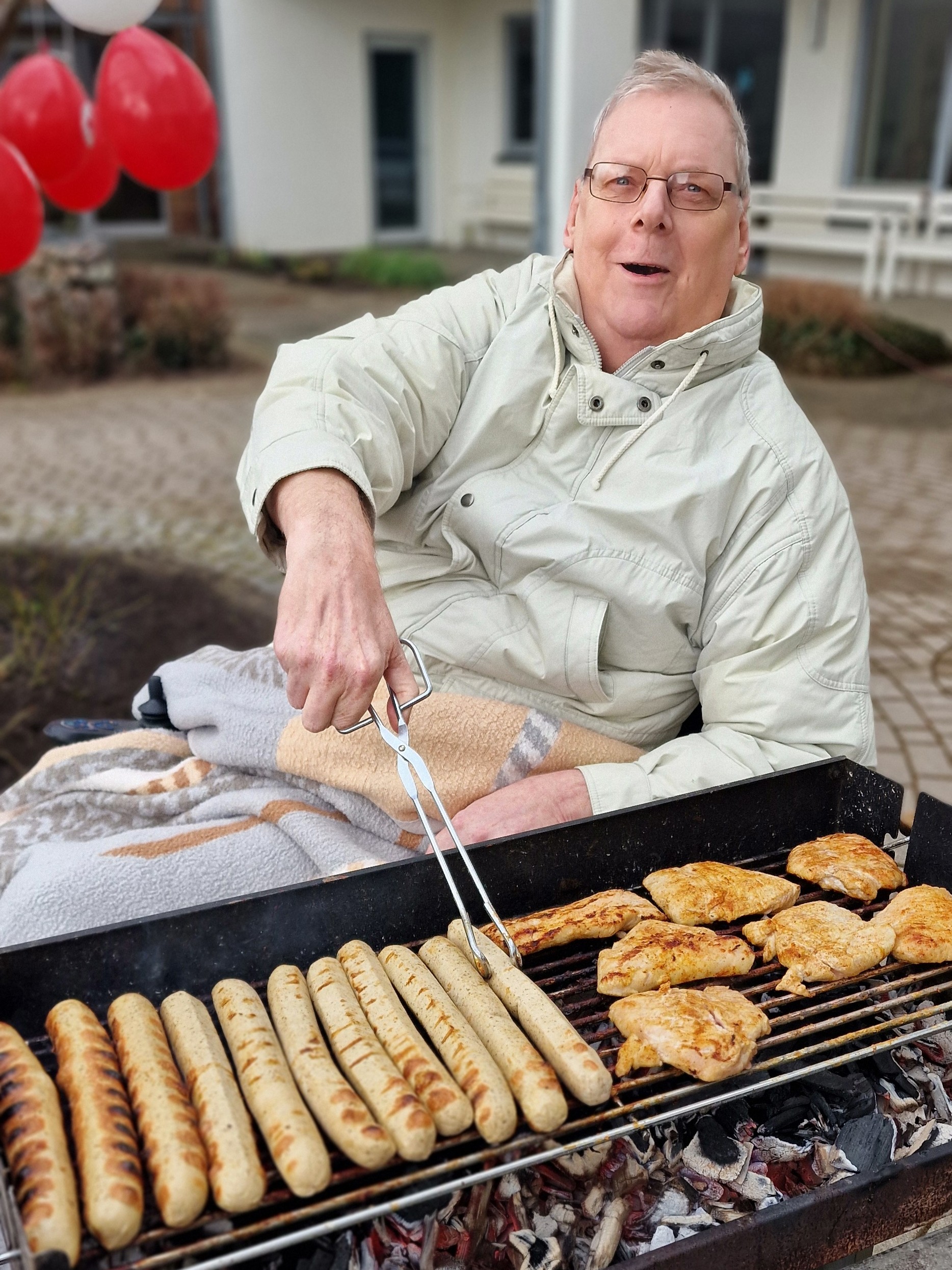 Bild zeigt Bewohnenden mit der Grillzange am Grill