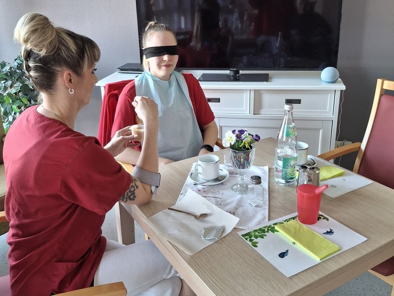 Bild zeigt die Auszubildende in der Rolle eines Heimbewohners beim Essen anreichen