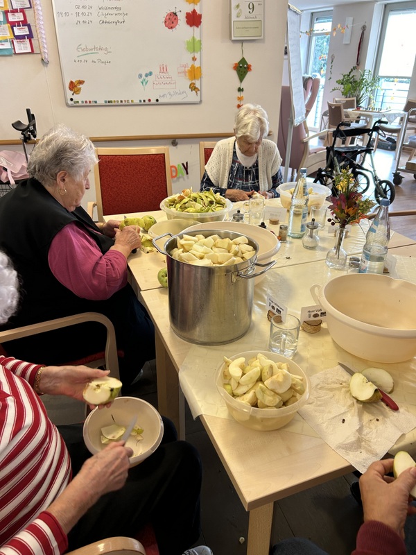 Bild zeigt mehrere Seniorinnen, welche Äpfel schälen und klein schneiden in Vorbereitung zum Kuchen backen