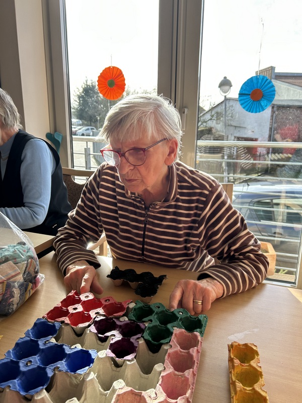 Bild zeigt eine Besucherin der Tagespflege mit einem von den Mitarbeitenden und den Gästen selbst erstellten Gedächtnisspiel aus Eierkartonpaletten - eine Art Tetrisspiel