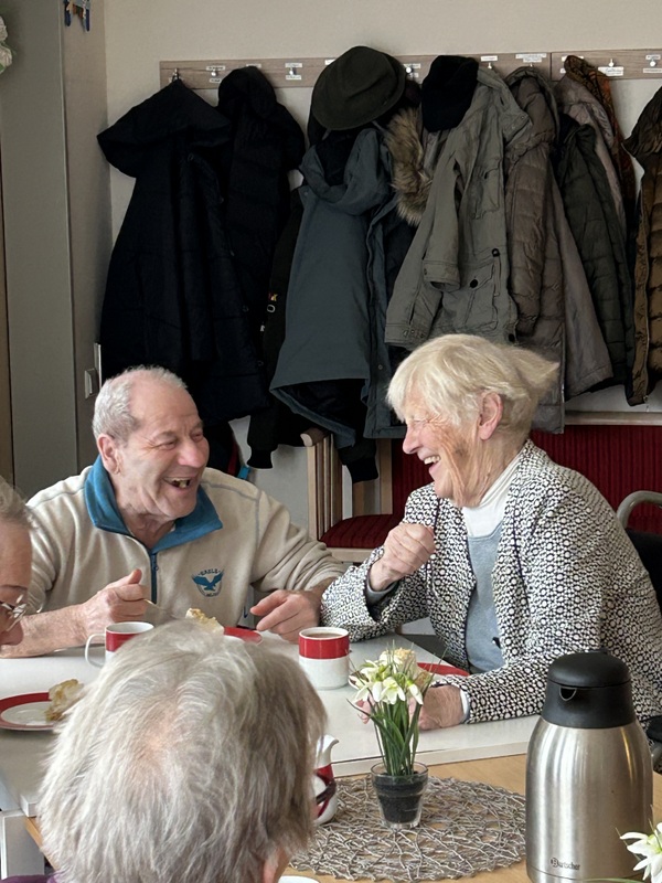 Bild zeigt mehrere Tagesgäste lachend an der Kaffeetafel 