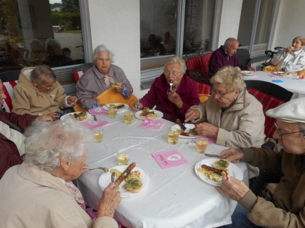 Gruppe von Senioren sitz am Tisch und ißt gegrilltes