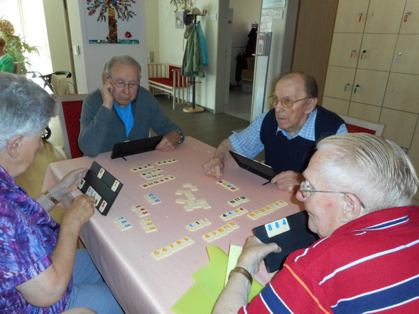 Gruppe von Senioren beim Rummy spielen - wie Rommè nur mit Spielsteinen