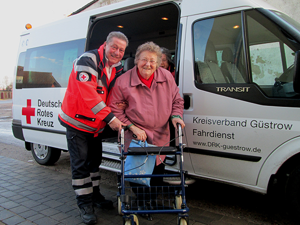DRK Transportbus mit Seniorein Und Fahrer davor stehend