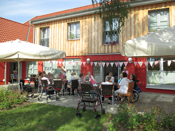 Gruppe von Senioren sitzt auf der Terrasse bei Kaffee und Kuchen
