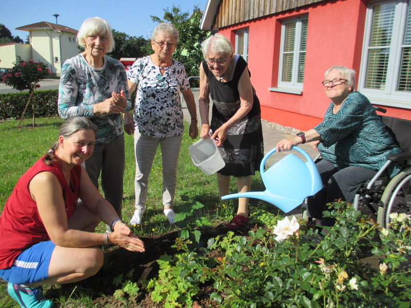 Bild zeigt Gäste der Tagespflege bei der Gartenarbeit im kleinen Beet am Haus
