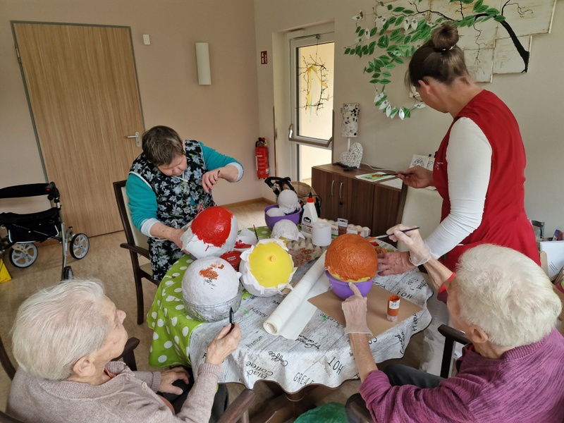 Bild zeigt Senioren am Tisch mit Pappmasche Luftballons bekleben